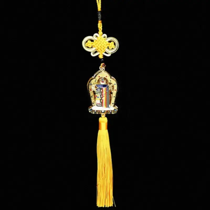 Traditional Tibetan emblem hanging charm featuring a gold frame, yellow mystic knot, and long yellow tassel on black background.