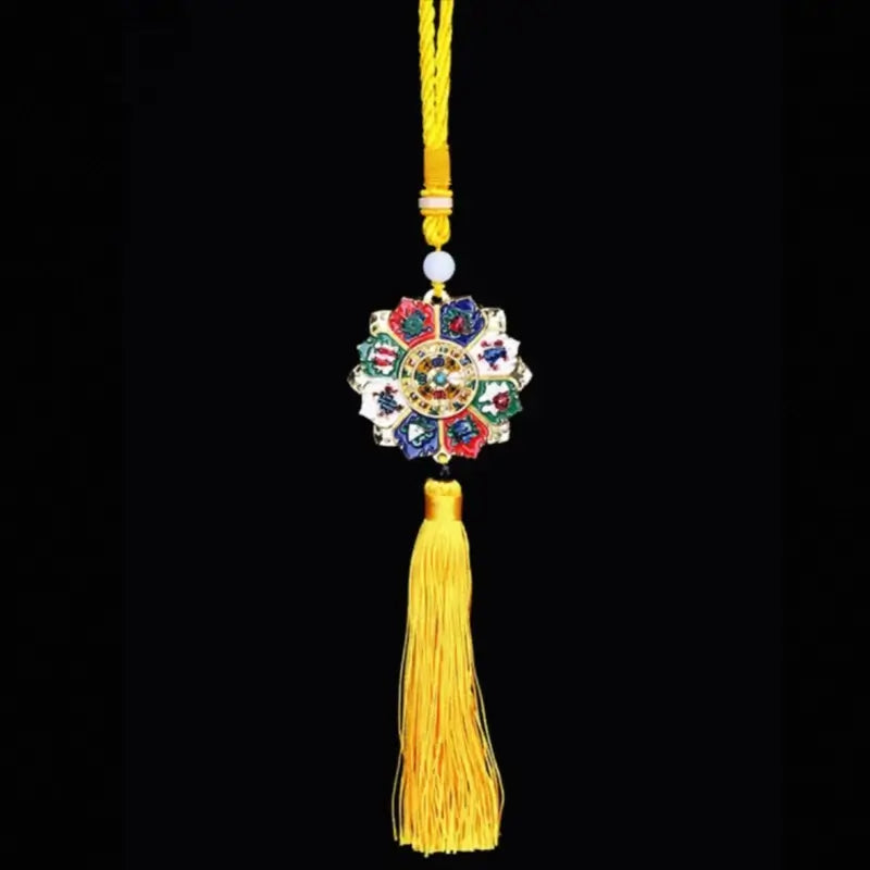 Circular Tibetan wheel charm with colorful auspicious symbols, white bead, and yellow tassel against a black background.