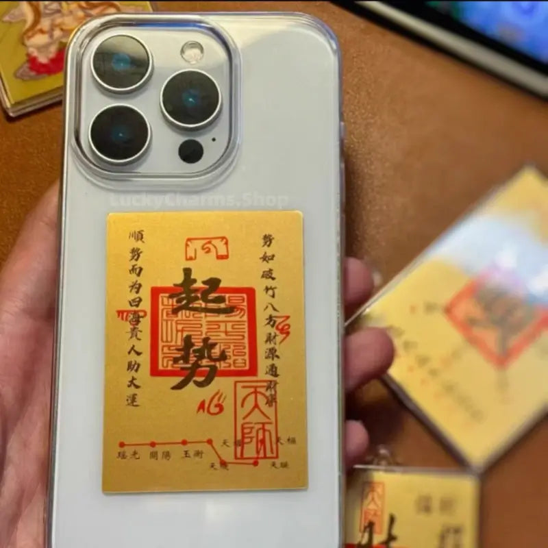 999 pure gold foil lucky decal displaying rising momentum blessing talisman attached to a smartphone.