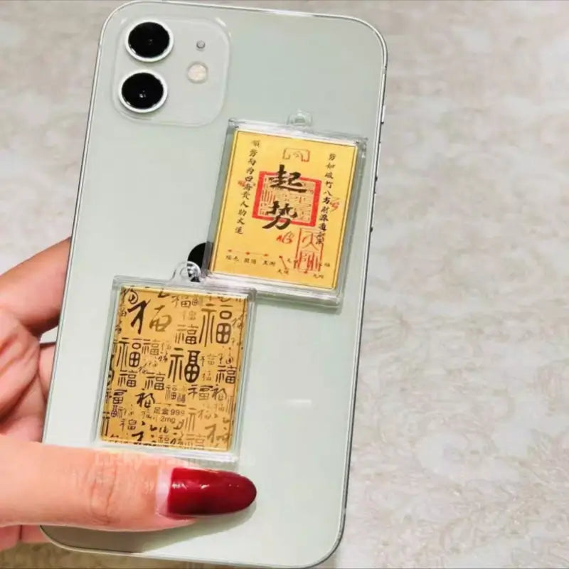 999 pure gold foil lucky charm decal with rising momentum blessing attached to smartphone case.