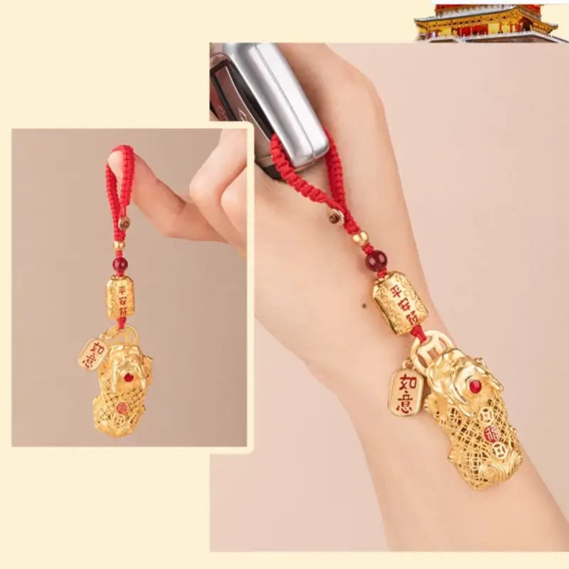Hand holding gold-plated brass Pixiu lucky pendant attached to a car key remote.