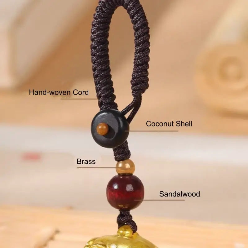 Material breakdown showing hand-woven cord, coconut shell, brass, and sandalwood beads.