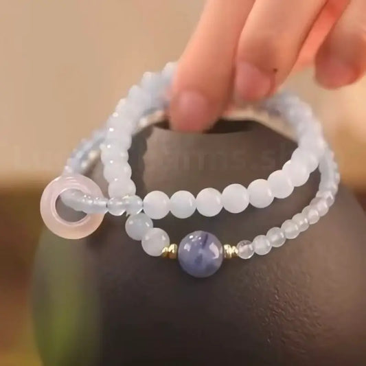 Light blue aquamarine and rose quartz double-layer energy bracelet displayed on a dark ceramic vase for home decor lifestyle