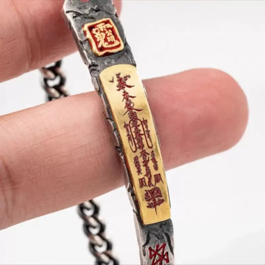 Close-up of a vintage Tibetan silver bracelet featuring a gold-plated Caishen Daoist talisman bar with red engraved characters.