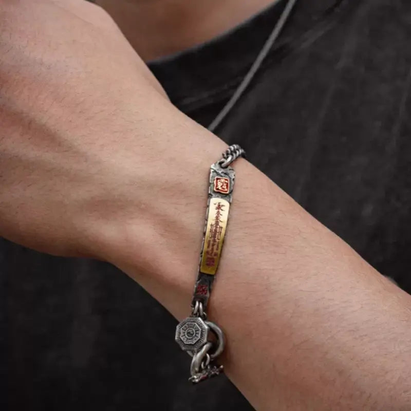 Side view of man wearing vintage silver chain bracelet with gold God of Wealth engraved plaque.