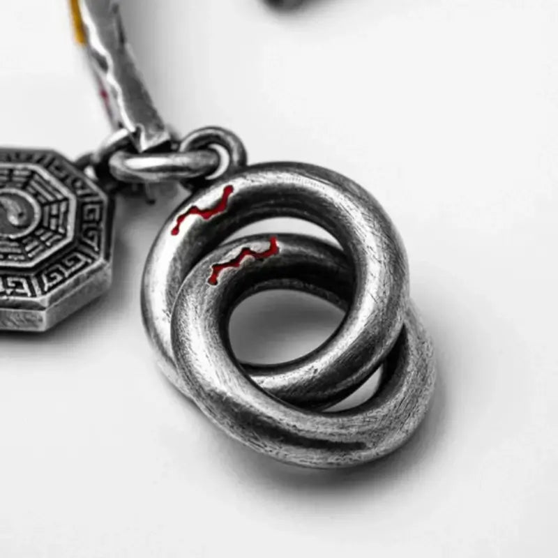 Macro shot of Tibetan silver ring clasp and Bagua charm with red enamel details.