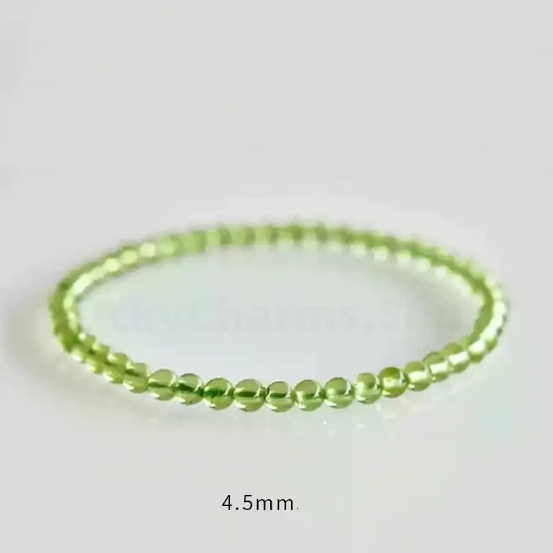 A delicate 4.5mm peridot gemstone single-layer stretch bracelet centered on a bright reflective surface, with a "4.5mm" size label.