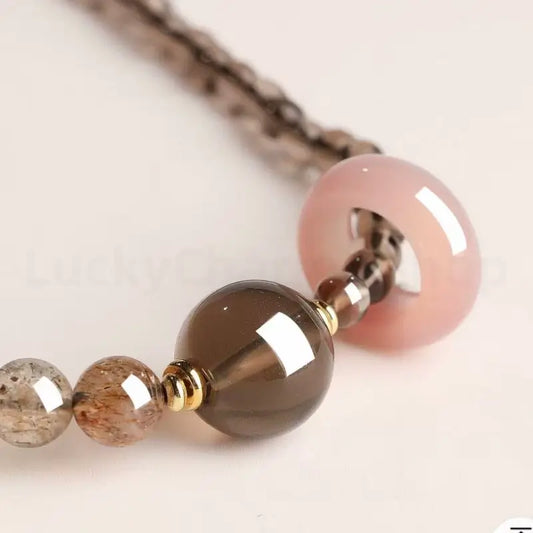 Close-up detail of a glossy dark brown smoky quartz crystal main bead on a spiritual healing energy bracelet