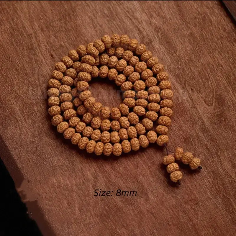 Coiled 8mm Nepalese Rudraksha 108 bead mala bracelet displayed on a wood background.