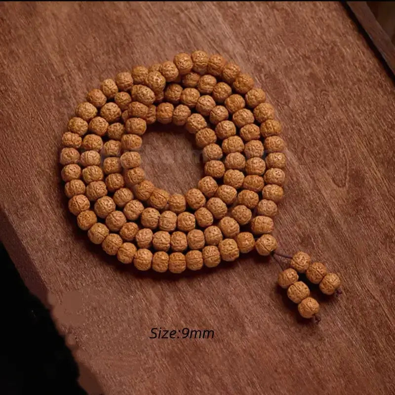 A 9mm medium-sized natural Rudraksha 108 prayer bead strand displayed on a wooden surface, showing balanced bead uniformities for meditation.