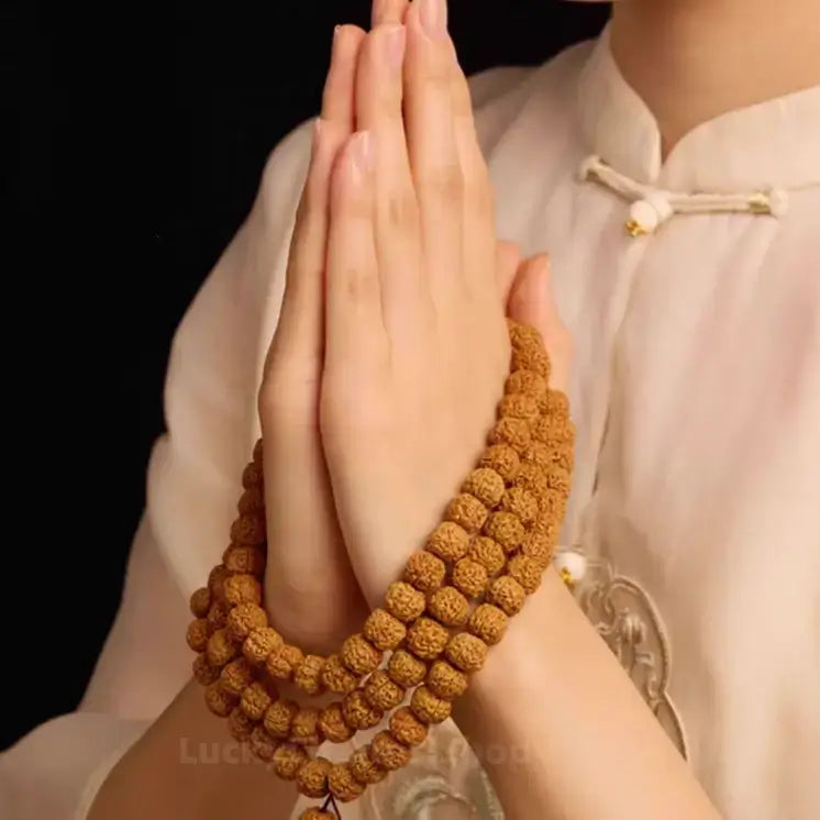 Hands joined in prayer wearing a wrapped Nepalese Rudraksha 108 bead mala bracelet.
