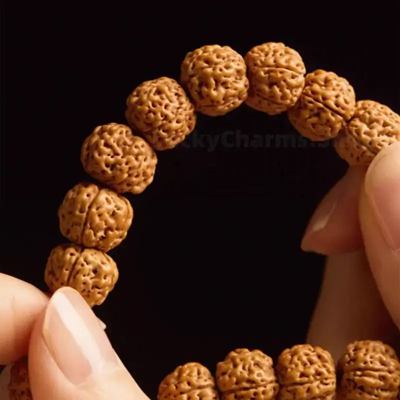 Close-up view of hands inspecting natural textured Nepalese Rudraksha beads strung on a line.