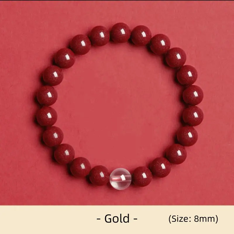 8mm natural cinnabar Gold element energy bracelet featuring a clear white crystal accent bead on red background.
