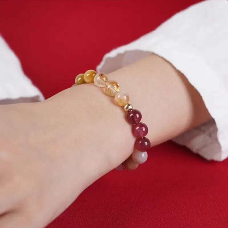 Natural gemstone Five Elements balance bracelet worn on a woman's wrist over a white sleeve.