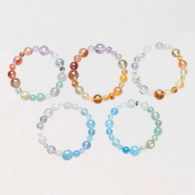 Five natural crystal mixed bead bracelets aligned in Five Elements combinations on white background.