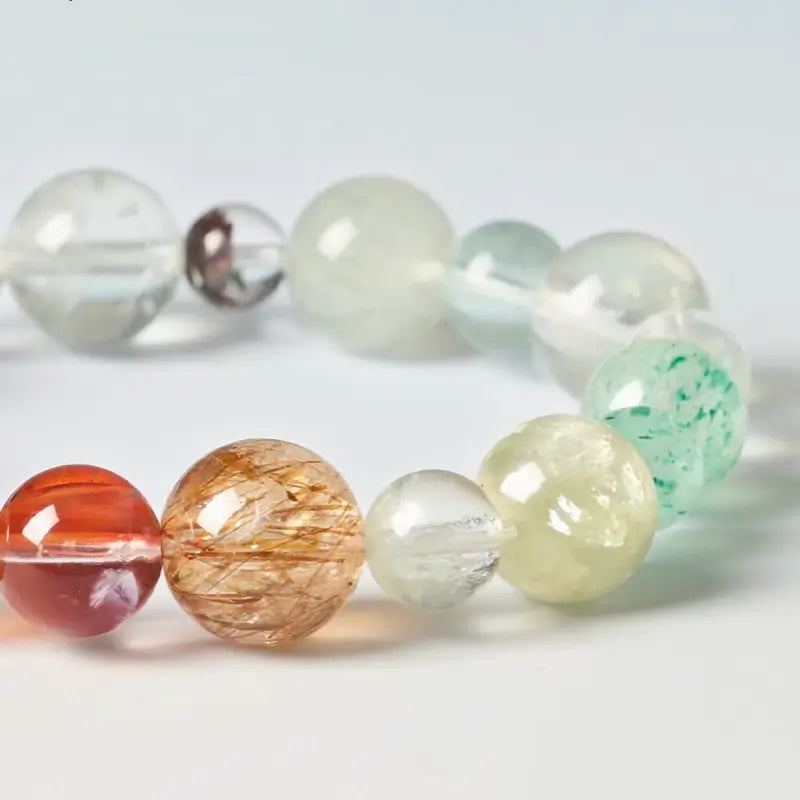 Close-up view of natural gemstone beads showing rutilated quartz, strawberry quartz, and green fluorite.