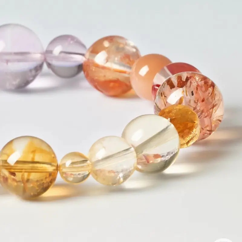 Close-up detail of citrine, sunstone, and amethyst natural crystal beads on a beaded bracelet.