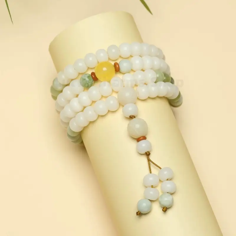 Front view of coiled white Bodhi seed bracelet with yellow accent bead mounted on a cylinder stand.