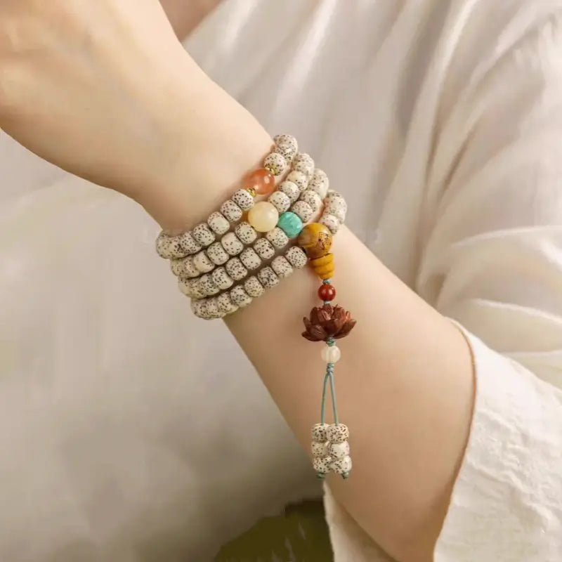 Multi-layer star moon Bodhi seed bracelet with carved wood lotus pendant wrapped around a wrist.