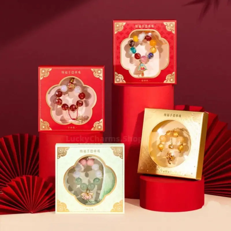 Four Palace Museum beaded phone charms packaged in decorative Chinese red and gold gift boxes.