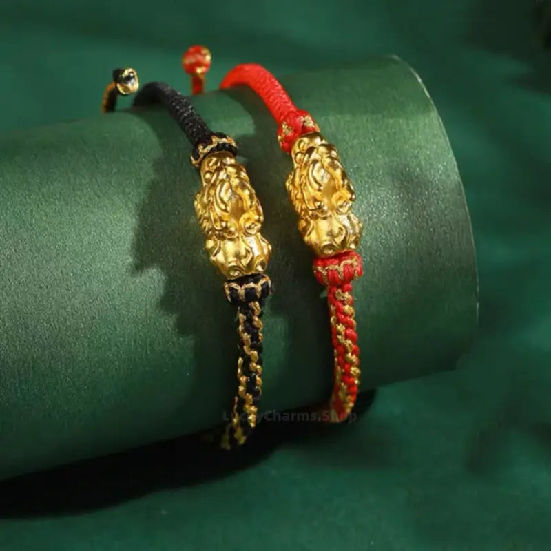 Pair of Palace Museum gold-plated Pixiu couple bracelets on black and red braided cords.