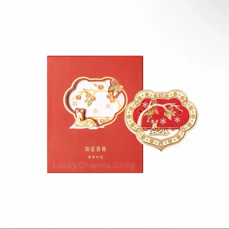 Pink enamel lotus Ruyi solid perfume compact with gold swallows displayed with jade bead strand and flowers.