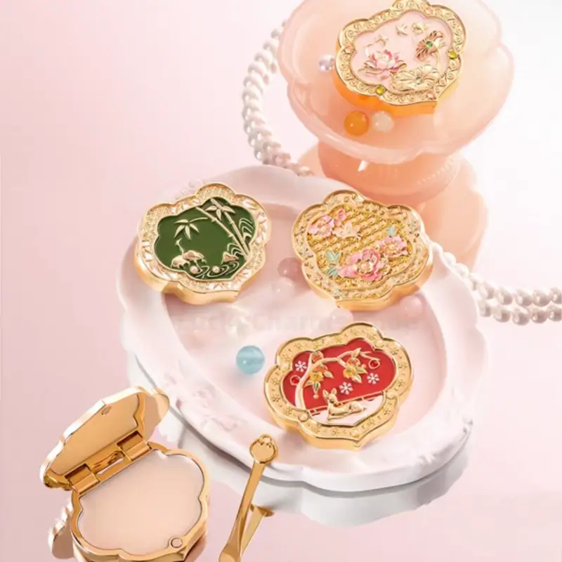 Collection of four Ruyi-shaped enamel solid perfume compacts on white decorative tray with balm applicator tool.