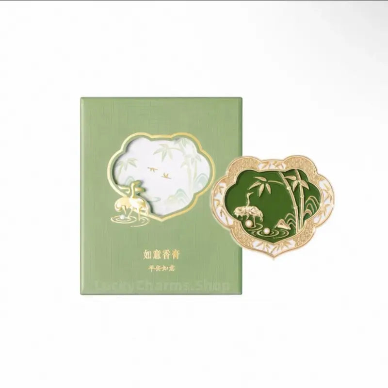 Palace Museum green enamel crane Ruyi solid perfume compact next to its light green decorative gift box.