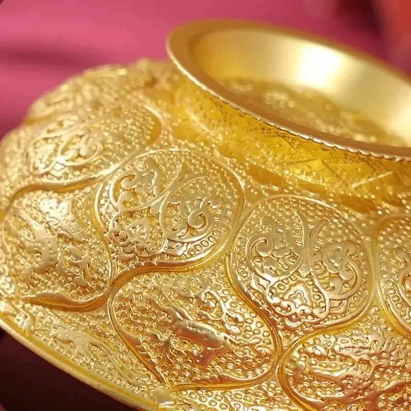 Close-up of ornate embossed lotus petals and animal carvings on gilded gold bowl magnet.