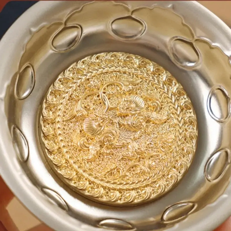 Macro detail of gilded golden center medallion with intricate Chinese lion carvings on silver bowl.