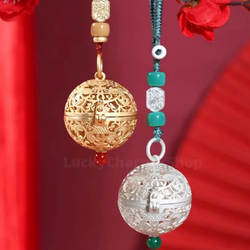 Gold and silver filigree spherical sachet pendants with ornate floral carvings hanging on braided cords.