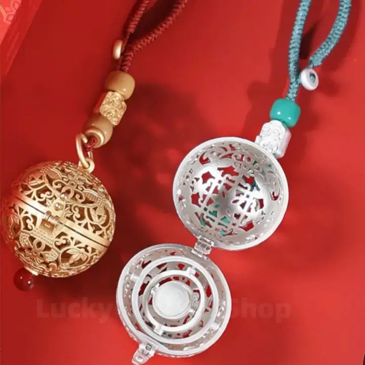 Open silver hollow locket sachet showing internal gimbal mechanism alongside a closed gold sachet pendant.