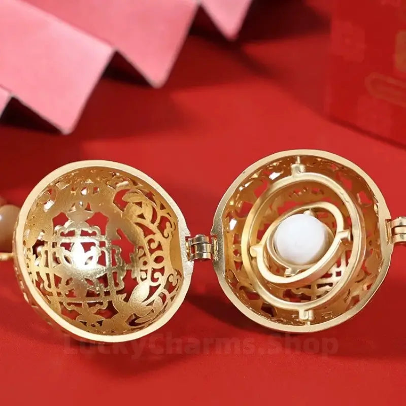 Close-up of open gold filigree ball sachet pendant displaying inner gyroscopic incense bead holder.