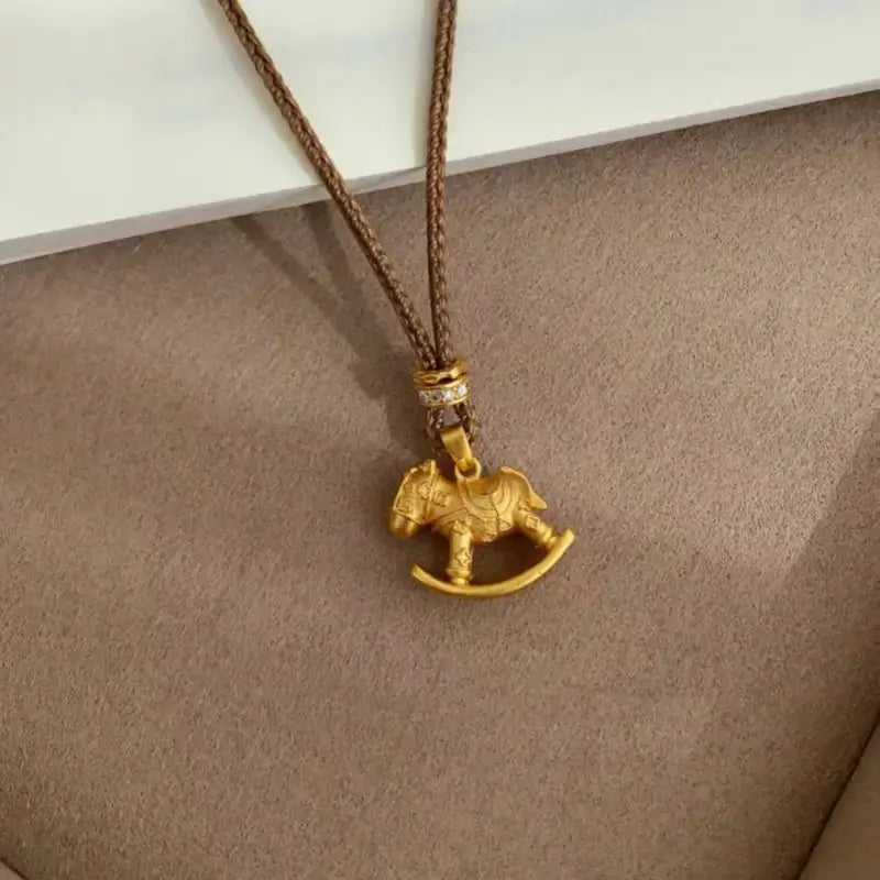 Gold-plated carousel rocking horse pendant on a adjustable brown cord necklace.
