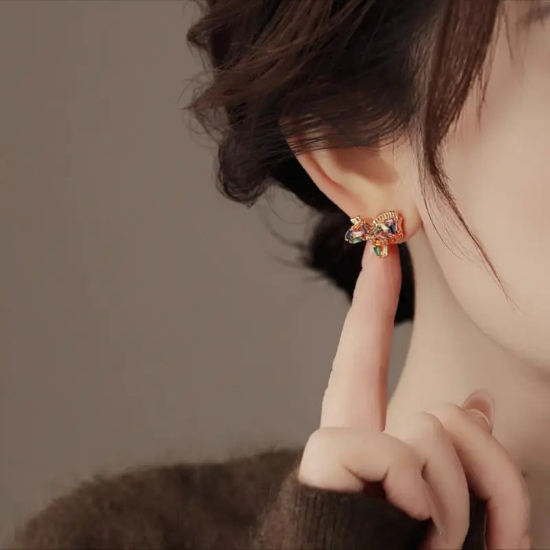 Close-up of model wearing colorful baguette zircon horse stud earring.