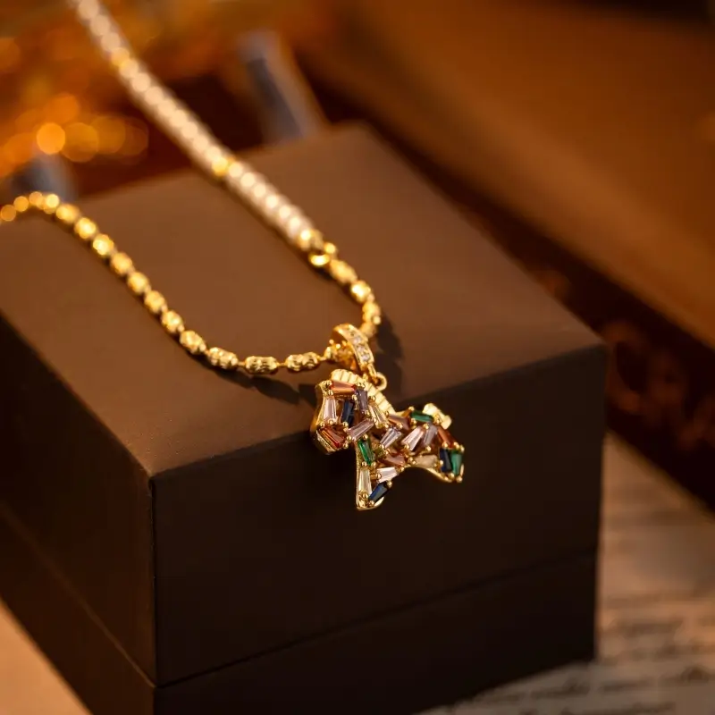 Gold half-pearl half-chain necklace featuring a colorful zircon pony horse pendant resting on box.
