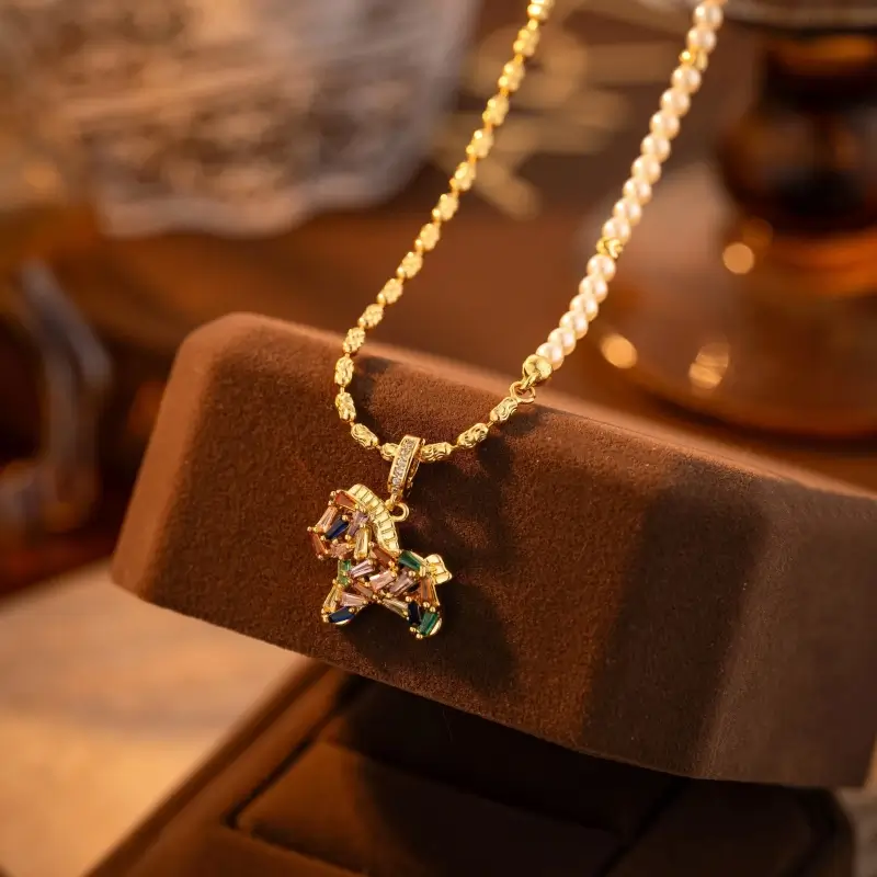 Close-up of gold chain and pearl necklace with a vibrant multicolor cubic zirconia pony pendant.
