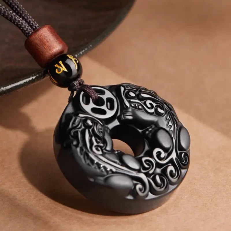 Black obsidian Pixiu peace buckle protection pendant with ancient coin motif, sandalwood bead, and cord.