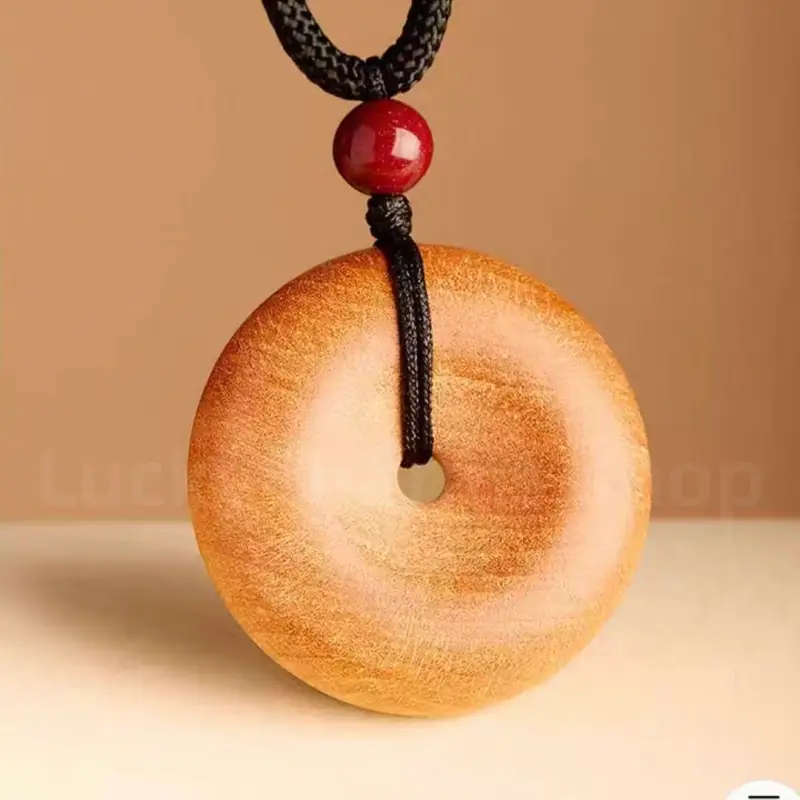 Close-up of carved peach wood donut pendant featuring smooth wood grain finish.