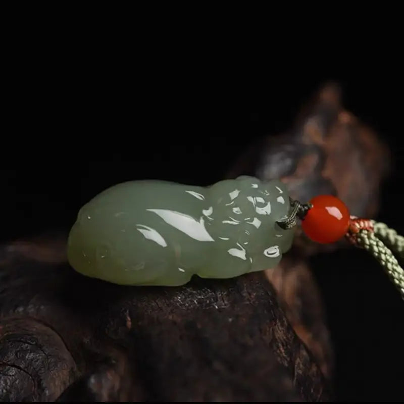 Side profile of a carved Hetian jade Pixiu wealth charm resting on dark rustic wood.