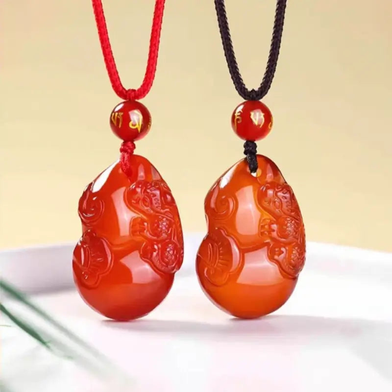Red agate gourd Pixiu pendants with mantra bead on red and black braided cords.