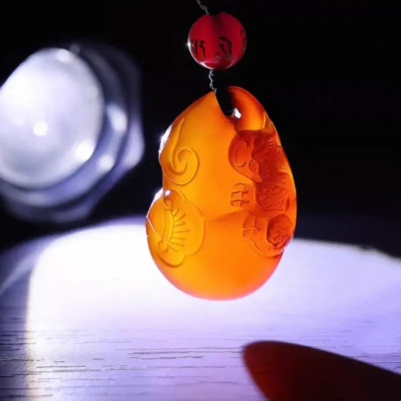 Backlit view showing translucent quality of red agate Pixiu gourd charm.