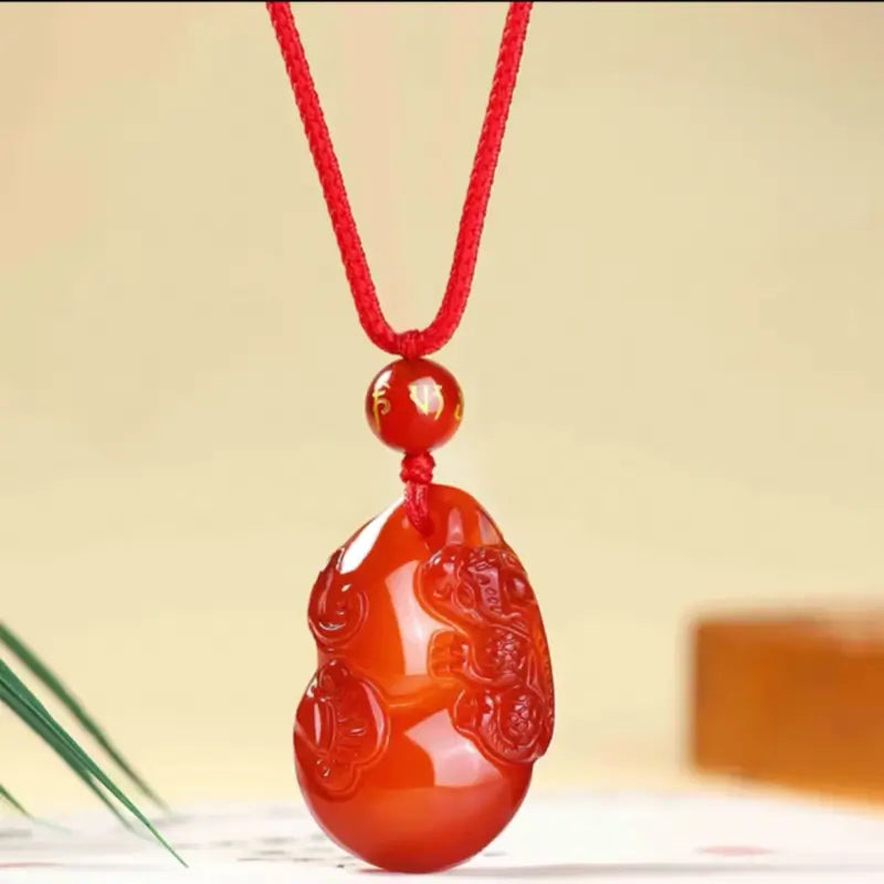 Natural red agate Pixiu gourd pendant with mantra bead on a red cord necklace.