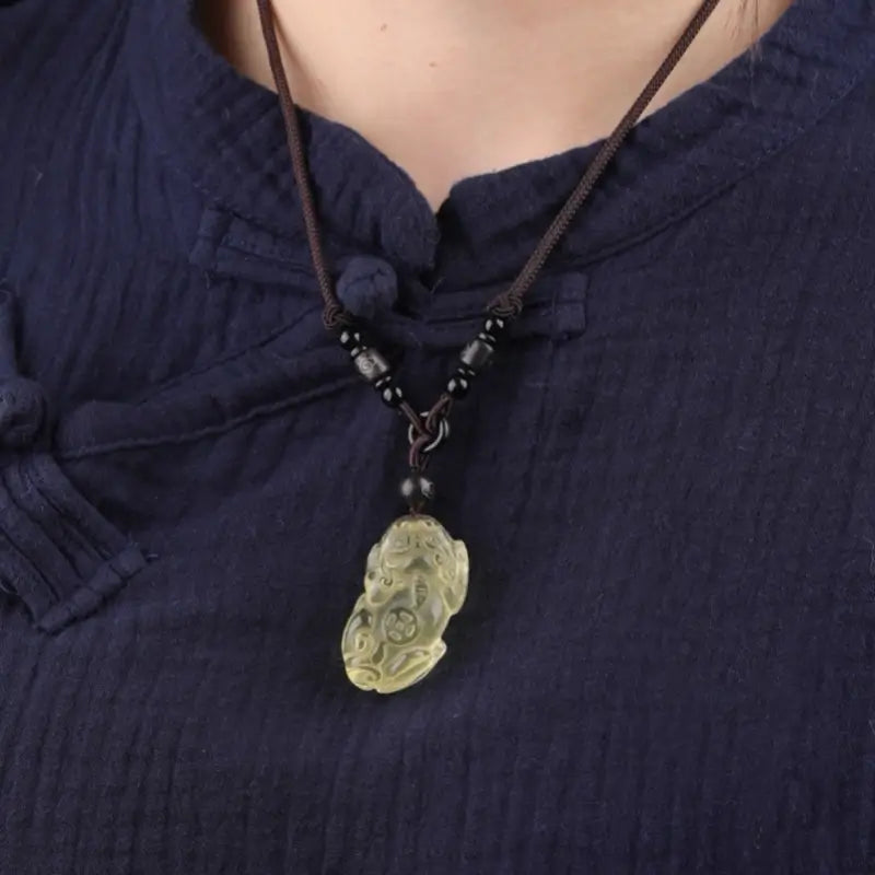 Model wearing a natural yellow citrine Pixiu necklace over a traditional navy blue top.