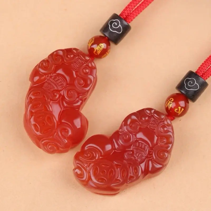 Back view of carved natural red agate Pixiu pendants displaying lucky ancient coin patterns.