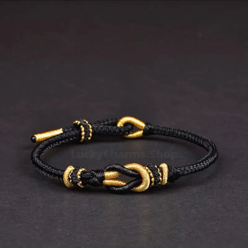 Black braided rope bracelet featuring a gold-wrapped Never Part knot centerpiece.