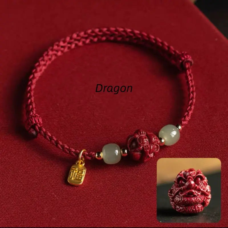 Red braided string bracelet with carved Dragon zodiac cinnabar bead, Hetian jade, and gold Fu tag.