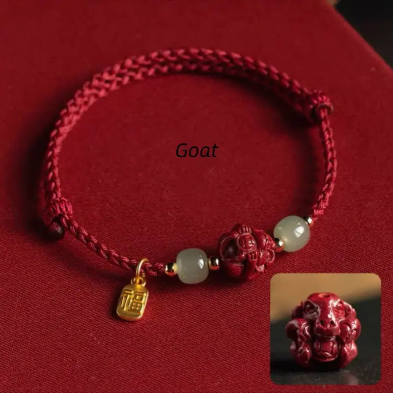Red cord lucky charm bracelet with hand-carved Goat zodiac cinnabar bead and Hetian jade accents.