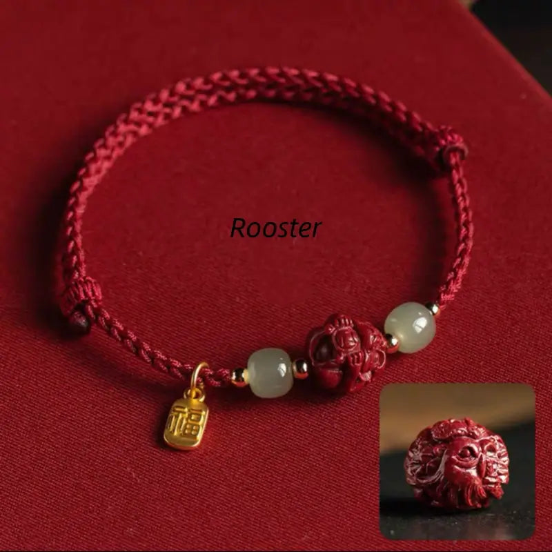 Chinese zodiac red braided bracelet showing carved Rooster cinnabar bead and gold Fu blessing pendant.