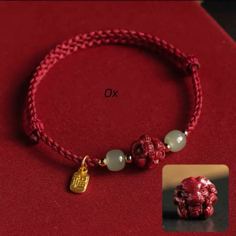 Chinese red string fortune bracelet featuring carved Ox zodiac cinnabar charm bead and Hetian jade.
